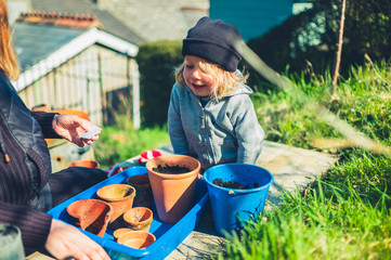 Mother and preschooler planting seeds in pots