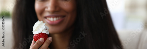 Fotografía Close-up of african-american young woman holding strawberry with whipped cream