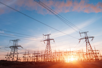 Wall Mural - electric network of pylons against a cloudy sky and a green meadow
