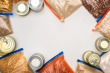 Wall Mural - top view of cans and groats in zipper bags on white background, food donation concept