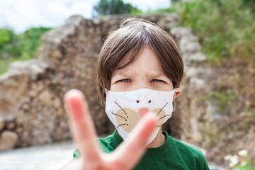 Little boy holds up two fingers for victory over Covid-19 Pandemic