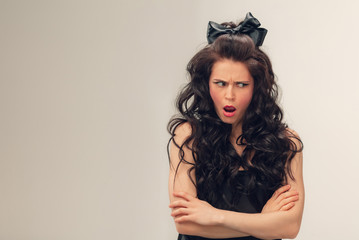 Angry asking. Portrait of beautiful young woman on grey studio background. Caucasian cute brunette female model with long curly hair. Concept of beauty, fashion, cosmetics. Copyspace for ad.