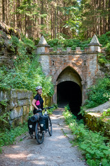 Schwarzenberg floating canal Woman with bike standing infront of the historic canal. A woman cyclist relaxing after sport. Bikepacking, Sumava, Bohemian Forest, Böhmerwald, Czech Republic.