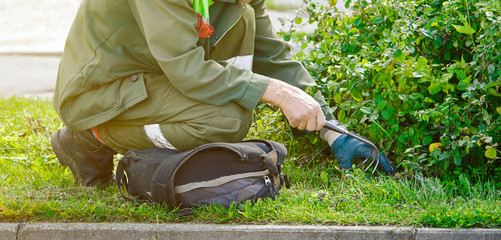 Municipal gardener with handled garden cultivator help street gardens around the city grow to their full potential by providing year-round care including weeding, pruning, and other maintenance