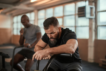 Fit young man exhausted after stationary bike workout session