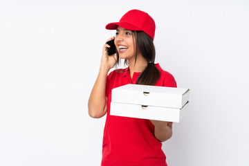 Young Pizza delivery girl over isolated white background keeping a conversation with the mobile phone