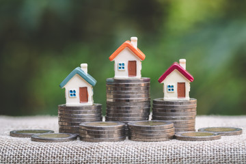 Wall Mural - Mini house on stack of coins, Concept of Investment property, Investment risk and uncertainty in the real estate housing market.