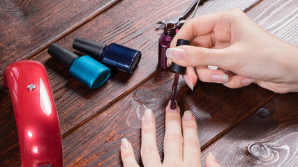 Wall Mural - A woman makes a gel manicure. The girl paints her nails with gel Polish. Nail salon, procedure, SPA. Home nail care. Manicure tools. Beauty, nail art, nail dryer, Glamour. 