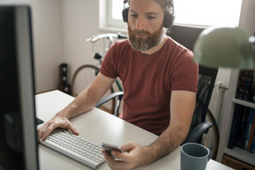 Wall Mural - Bearded man working on computer from his home office