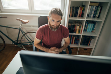 Wall Mural - Bearded businessman working on computer from his home office