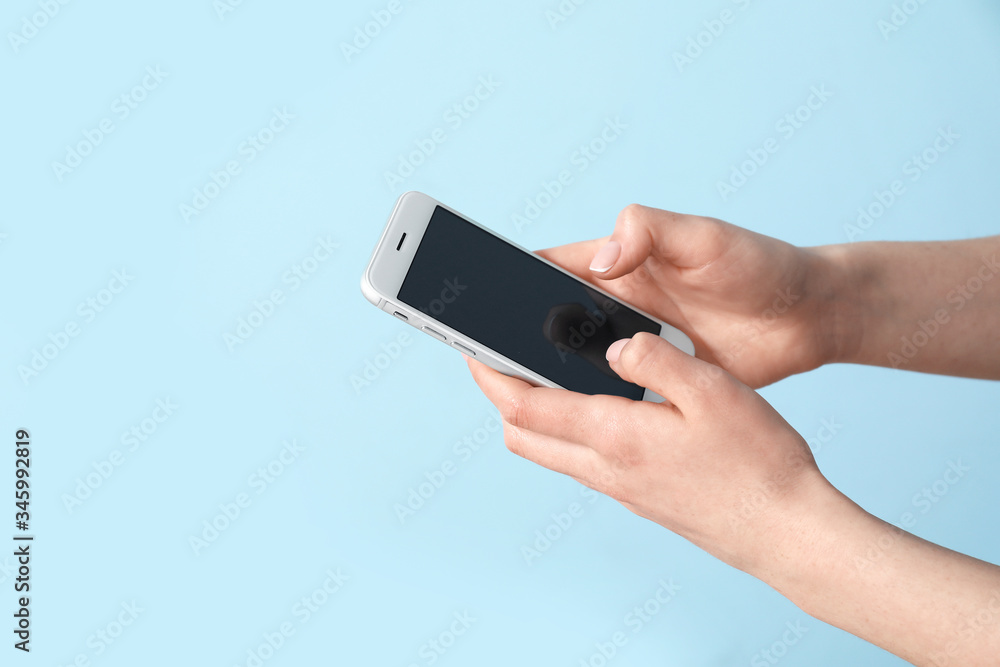 Female hands with mobile phone on color background