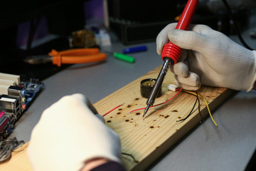 worker's hands solder with soldering iron in the workshop close up