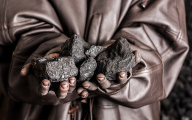 Miner holding coal stones. Hard worker.  