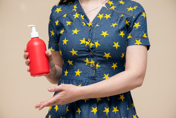 Wall Mural - Woman showing in hand a red liquid soap bottle close up. Hand washing.