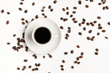 A cup of black coffee on a white isolated background with scattered coffee beans.