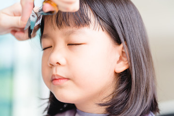 Wall Mural - Asian Mother cutting hair to her daughter by herself at home.Stay at home stay safe from Covid-19 Coronavirus.Hairstyle online class, Stay home and life during lockdown.Happy smiley face from kid girl