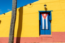 Cuban Flag In A Blue Window With A Yellow Wall