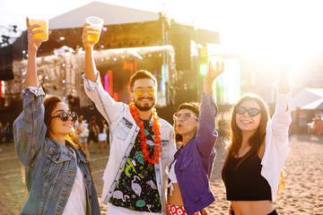 Wall Mural - Young happy friends drinking beer and having fun at music festival together. Beach party, summer holiday, vacation concept. Friendship and celebration concept.