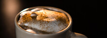 Close Up Of Delicious Cappuccino With Cinnamon And Milk Foam In Cup On Dark Table.