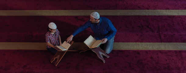 father and son in mosque praying and reading holly book quran together