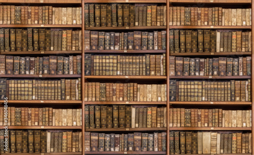 Defocused and blurred image of old antique library books on shelves for use in video conferencing background © steheap
