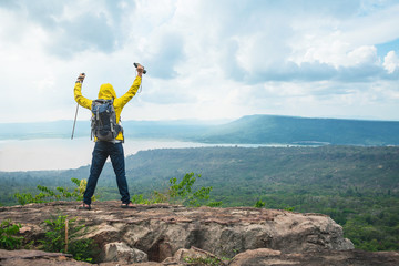 Hikers with backpacks relaxing on top of a mountain and enjoying the view of valley. Young man with backpack enjoying sunset on the peak of mountain .Travel hiking.