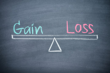 Text word gain and loss balance on seesaw drawing writing on chalkboard or blackboard background. Concept of gain and loss analysis in business, financial management and investment.