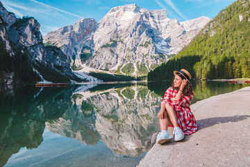 Wall Mural - woman in red checkered dress with straw hat looking at mountain lake