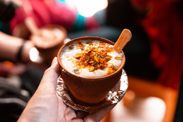 Indian popular drink lassi (traditional dahi yogurt-based drink) in clay cup with various topping on the street in Varanasi.