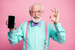 canvas print picture - Portrait of energetic positive old man hold new cellphone show okay sign recommend choose good modern technology wear teal turquoise shirt violet bow tie isolated pastel pink color background