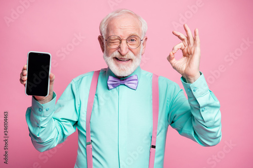Fotomural Portrait of energetic positive old man hold new cellphone show okay sign recomme