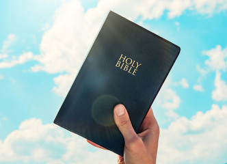 Canvas Print - man hand Holy Bible sky background
