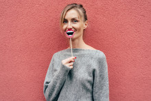 Stylish Joyful Young Blonde Woman Holds Paper Prop Lips And Posing. Comic Portrait On A Pink Background.