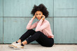 © mimagephotos - beautiful african american woman sitting on floor outside talking with cellphone