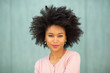 © mimagephotos - front portrait attractive young black woman with afro hairstyle by green background