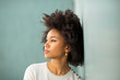 © mimagephotos - Close up young african american woman with afro hair leaning against wall looking away