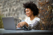 © mimagephotos - smiling young african american woman sitting with laptop