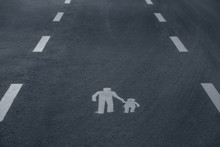Pedestrian Sign Painted White On Asphalt Depicting Adult And A Child, Framed By A Dashed Lines