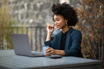 Wall Mural - black businesswoman sitting outside with laptop computer