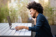 © mimagephotos - smiling young african american business woman sitting with laptop and mobile phone