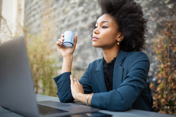 Close up black businesswoman sitting with laptop and coffee at table