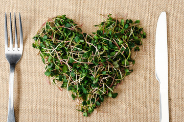 Poster - top view of fresh microgreen arranged in heart on sackcloth with cutlery