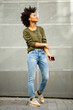 © mimagephotos - Full length beautiful young african woman with mobile phone and earphones