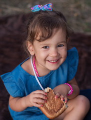 delicious sweet pastries in children 's hands. a sacky little girl holds a sweet bun in her hands.