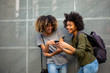 © mimagephotos - happy young african american women friends with mobile phone and bags