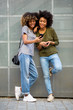 © mimagephotos - Full body two african american young woman with cellphone
