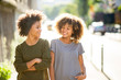 © mimagephotos - two black female friends walking and smiling in city