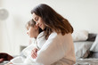 © deniskomarov - Mother hugging from back loving sleepy daughter.