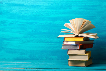 Composition with vintage old hardback books, diary, fanned pages on wooden deck table and red background. Books stacking. Back to school. Copy Space. Education background.