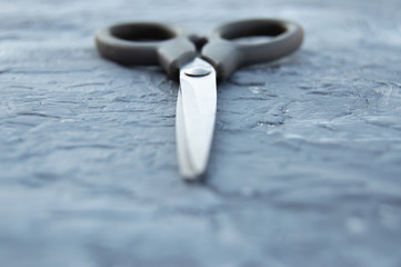 Scissors on a gray, frayed background.